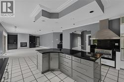 Kitchen featuring a large island with dark countertops and stainless steel cabinetry, a stainless steel range hood, and white tile flooring - 