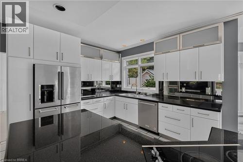 Modern kitchen featuring white cabinetry, dark countertops, and stainless steel appliances - 44 St Andrew'S Drive, Brantford, ON - Indoor Photo Showing Kitchen