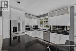 Modern kitchen featuring white cabinetry, dark countertops, and stainless steel appliances - 