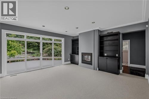 Contemporary living space featuring a built-in fireplace, recessed lighting, crown molding, and expansive sliding glass doors - 44 St Andrew'S Drive, Brantford, ON - Indoor