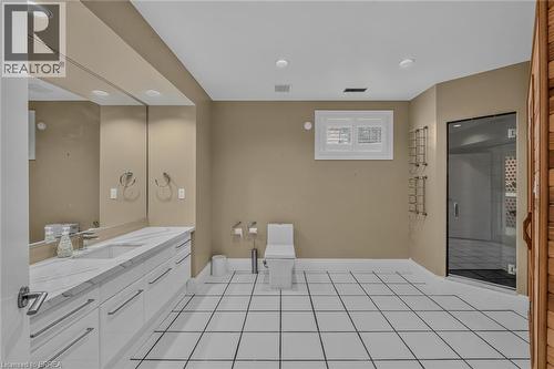 Bathroom featuring white square tile flooring with dark grout, a spacious dual vanity with white cabinetry and a light-toned countertop, a built-in toilet, a sauna with a wood door, and a glass-enclos - 44 St Andrew'S Drive, Brantford, ON - Indoor Photo Showing Bathroom
