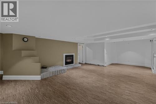 Spacious room featuring wood-finish flooring, a contemporary fireplace with a stone hearth, and a built-in architectural detail - 44 St Andrew'S Drive, Brantford, ON - Indoor Photo Showing Other Room With Fireplace