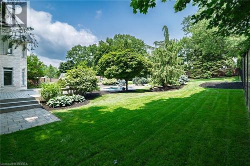 Spacious backyard featuring extensive lawn, mature trees, a multi-level deck, and a paver patio - 44 St Andrew'S Drive, Brantford, ON - Outdoor