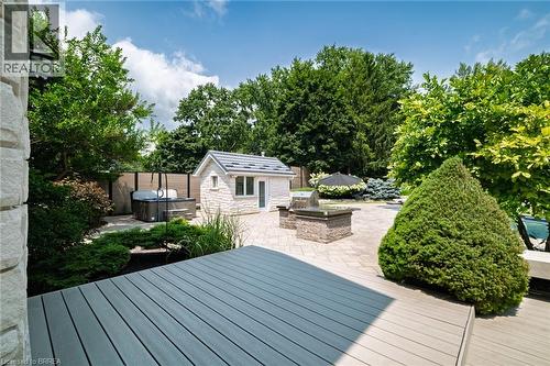 Expansive outdoor living area featuring a composite deck, paver patio, stone-clad shed, built-in BBQ grill, and mature landscaping - 44 St Andrew'S Drive, Brantford, ON - Outdoor With Deck Patio Veranda