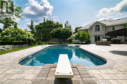 Oval-shaped swimming pool featuring a diving board and built-in steps - 44 St Andrew'S Drive, Brantford, ON - Outdoor With In Ground Pool With Deck Patio Veranda