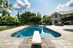 Oval-shaped swimming pool featuring a diving board and built-in steps - 