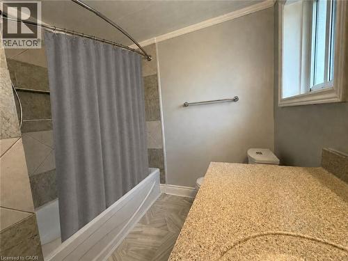Bathroom featuring a built-in tub with tile surround, a spacious vanity with a textured countertop and integrated sink, a toilet, and a window - 41 Edgemere Drive, Cambridge, ON - Indoor