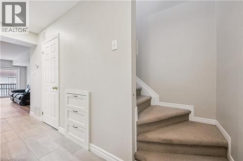 Hallway featuring light-toned large format tile flooring, a white six-panel door, built-in three-drawer cabinetry, and a carpeted staircase - 711 Johnston Park Avenue, Collingwood, ON - Indoor Photo Showing Other Room