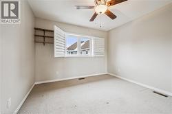 Room with a window featuring white plantation shutters, a ceiling fan with integrated lighting, and built-in shelving - 