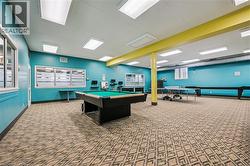 Spacious recreation room featuring patterned carpet flooring, teal wall paint, and a yellow structural beam - 