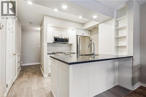 Kitchen featuring a central island with a sink and dark countertop, white shaker-style cabinetry, stainless steel appliances, a white subway tile backsplash, and recessed lighting - 711 Johnston Park Avenue, Collingwood, ON - Indoor Photo Showing Kitchen