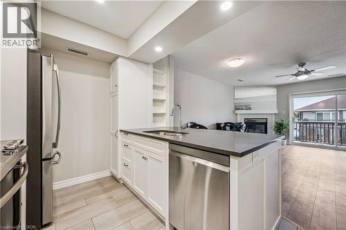 Modern kitchen island featuring a dark countertop, undermount sink with a gooseneck faucet, and an integrated stainless steel dishwasher - 711 Johnston Park Avenue, Collingwood, ON - Indoor Photo Showing Kitchen