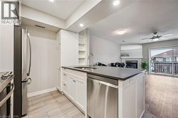Modern kitchen island featuring a dark countertop, undermount sink with a gooseneck faucet, and an integrated stainless steel dishwasher - 