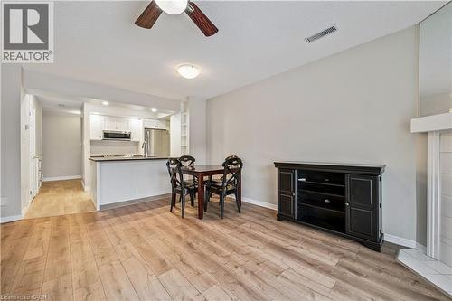 Open-concept living area with wood-finish flooring, a contemporary kitchen with white cabinetry and stainless steel appliances, and a breakfast bar - 711 Johnston Park Avenue, Collingwood, ON - Indoor