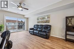 Living area featuring wood-finish flooring, a ceiling fan with integrated lighting, and a sliding glass door providing balcony access - 