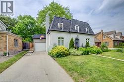 White stucco exterior with a dark gambrel roof, three dormer windows, and a prominent chimney - 
