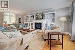 Spacious living area featuring hardwood flooring, a fireplace with a dark tile surround, and custom built-in shelving - 