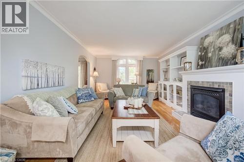 Expansive living area featuring light wood-finish flooring, a built-in fireplace with a tiled surround, and integrated custom cabinetry with shelving - 314 Glasgow Street, Kitchener, ON - Indoor Photo Showing Living Room With Fireplace