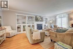 Living area with wood-finish flooring, a fireplace featuring a tile surround, and built-in shelving - 