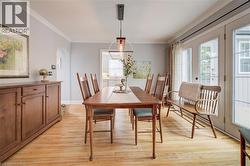 Dining area featuring wood-finish flooring, a contemporary linear pendant light, and crown molding - 