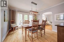 Dining area featuring wood-finish flooring, a contemporary chandelier, crown molding, and French doors leading to an exterior space - 