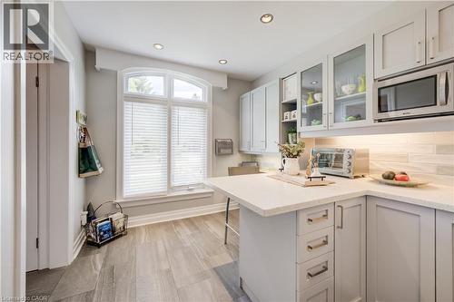 Kitchen featuring plank-style flooring, an arched window, recessed lighting, and light-toned cabinetry with glass-front accents - 314 Glasgow Street, Kitchener, ON - Indoor Photo Showing Kitchen