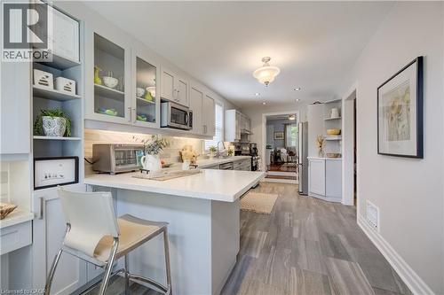 Contemporary kitchen featuring light gray cabinetry, quartz countertops, a tile backsplash, and wood-finish flooring - 314 Glasgow Street, Kitchener, ON - Indoor Photo Showing Kitchen