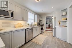 Kitchen featuring light gray cabinetry, stainless steel appliances, white countertops, and a subway tile backsplash - 