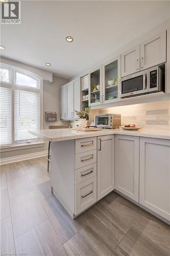 Kitchen featuring light gray cabinetry, built-in microwave, wood-finish tile flooring, recessed ceiling lighting, and an arched window - 314 Glasgow Street, Kitchener, ON - Indoor Photo Showing Kitchen