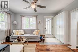 Living area featuring wood-finish flooring, light grey wall paint, and a ceiling fan with integrated lighting - 