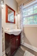 Bathroom vanity with a white integrated sink, dark wood-finish cabinetry, chrome faucet, and decorative mirror - 