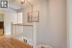 Upper-level landing featuring hardwood flooring and a white wooden staircase with a natural wood handrail - 