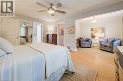 Bedroom featuring wood-finish flooring, ceiling fan with integrated lighting, and direct access to an additional living space - 