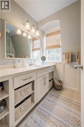Bathroom featuring a single vanity with a white countertop and undermount sink, white cabinetry with brushed nickel hardware, a rectangular framed mirror, and a wall-mounted light fixture with four sc - 314 Glasgow Street, Kitchener, ON - Indoor Photo Showing Bathroom