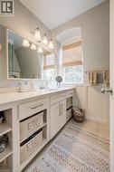 Bathroom featuring a single vanity with a white countertop and undermount sink, white cabinetry with brushed nickel hardware, a rectangular framed mirror, and a wall-mounted light fixture with four sc - 