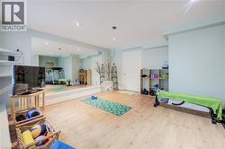Spacious interior room featuring light wood-finish flooring, a full-wall mirror, recessed lighting, and light blue wall tones - 