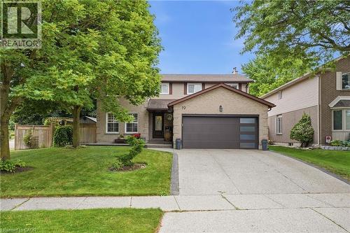 Brick and siding exterior featuring a two-car garage with frosted glass inserts, a paved driveway, and mature landscaping - 19 Alona Avenue, Cambridge, ON - Outdoor With Facade