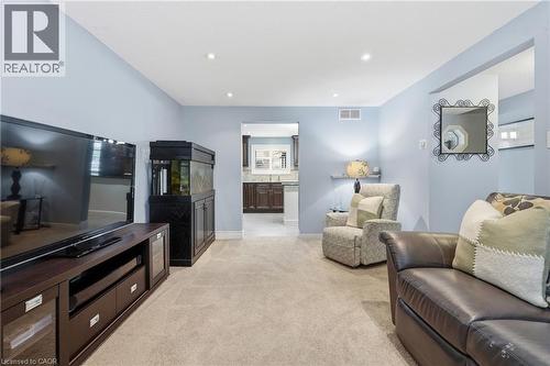 Carpeted living area featuring recessed lighting, light blue wall paint, and a defined entryway to a kitchen with dark wood-finish cabinetry and light-colored countertops - 19 Alona Avenue, Cambridge, ON - Indoor Photo Showing Living Room