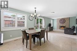 Dining area with tile flooring and a chandelier, opening to a living space featuring a brick fireplace - 