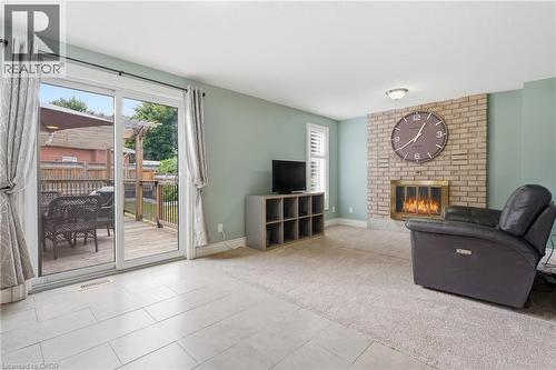 Living space featuring a brick fireplace, sliding glass door to an outdoor deck, and a combination of carpet and tile flooring - 19 Alona Avenue, Cambridge, ON - Indoor Photo Showing Living Room With Fireplace