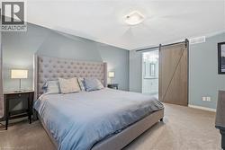 Carpeted bedroom with a light blue accent wall and a sliding barn door - 