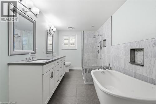 Contemporary bathroom featuring a freestanding soaking tub, a frameless glass shower enclosure with a built-in bench, and a double vanity with stone countertops - 19 Alona Avenue, Cambridge, ON - Indoor Photo Showing Bathroom