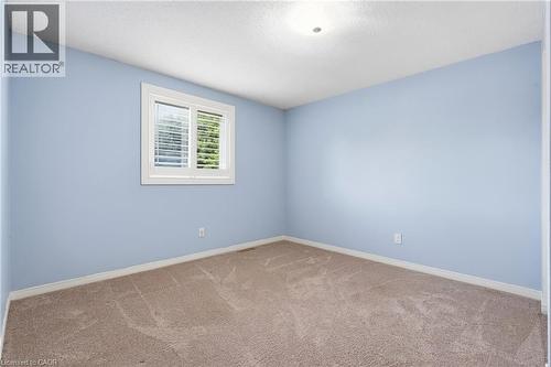 Bedroom with light blue walls, tan patterned carpet, white baseboards, and a single recessed ceiling light fixture - 19 Alona Avenue, Cambridge, ON - Indoor Photo Showing Other Room