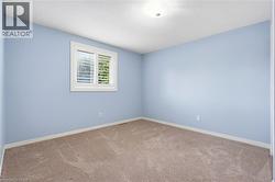 Bedroom with light blue walls, tan patterned carpet, white baseboards, and a single recessed ceiling light fixture - 
