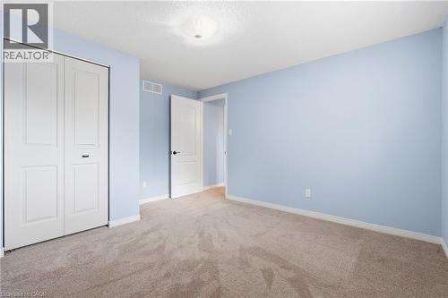 Carpeted room featuring a white bi-fold closet, a white paneled interior door with dark hardware, a ceiling light fixture, and light blue wall finishes - 19 Alona Avenue, Cambridge, ON - Indoor Photo Showing Other Room