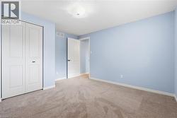 Carpeted room featuring a white bi-fold closet, a white paneled interior door with dark hardware, a ceiling light fixture, and light blue wall finishes - 