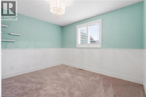 Room featuring paneled wainscoting, light-colored walls, carpet flooring, and a window with white shutters - 19 Alona Avenue, Cambridge, ON - Indoor Photo Showing Other Room