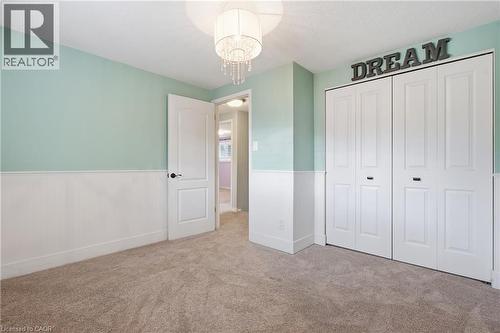 Bedroom featuring light green walls with white wainscoting, neutral carpet flooring, and a crystal chandelier - 19 Alona Avenue, Cambridge, ON - Indoor
