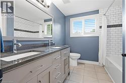 Bathroom featuring a double vanity with polished chrome fixtures and stone countertops - 