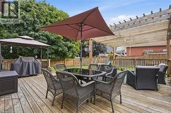 Expansive outdoor wood deck featuring a pergola with a retractable shade cover, wood privacy fencing, and mature surrounding trees - 